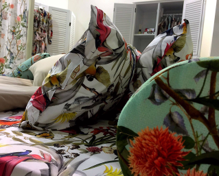 Decorative pillows and bedding with vibrant tropical bird and floral prints. The bright colors create a lively, cozy atmosphere in a bedroom setting.